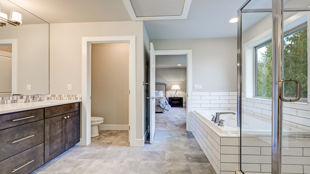 Modern bathroom remodel in Tuscaloosa featuring a walk-in shower with glass doors, a freestanding bathtub, and elegant tilework.